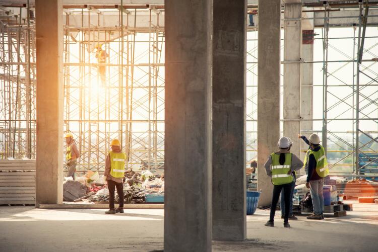 Construction workers inside a building under construction. They are surrounded by scaffolding and various construction materials, indicating the installation of essential systems such as Flowflex plumbing fittings and valves.