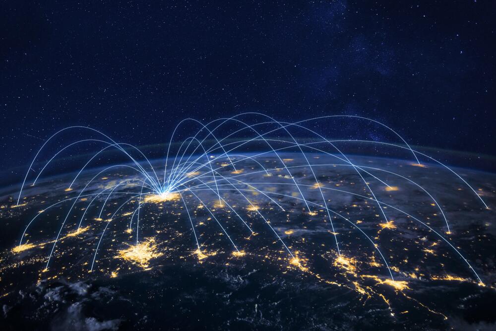 A night-time satellite view of the Earth, highlighting pathways symbolising global connections. Blue lines arching across the globe represent the international reach of Flowflex products and relationships.