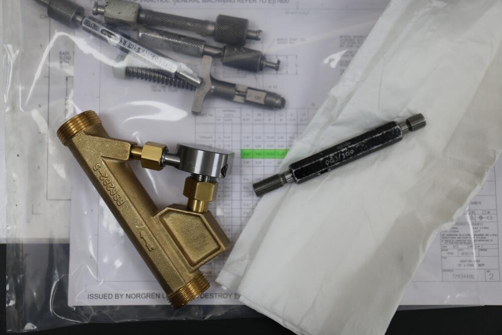 A Flowflex brass valve component and a threaded tool laid out on technical drawings, highlighting Flowflex’s commitment to precision engineering and quality control in their product range.