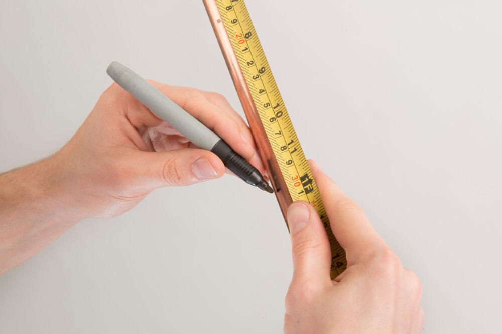 Image showing an installer marking his pipe to cut accurately to size